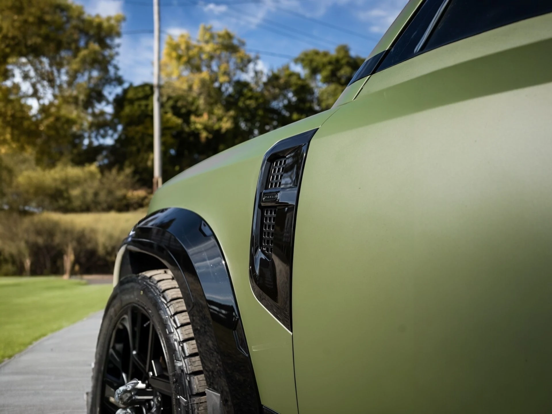 Close detail of a green vehicle fender and wheel
