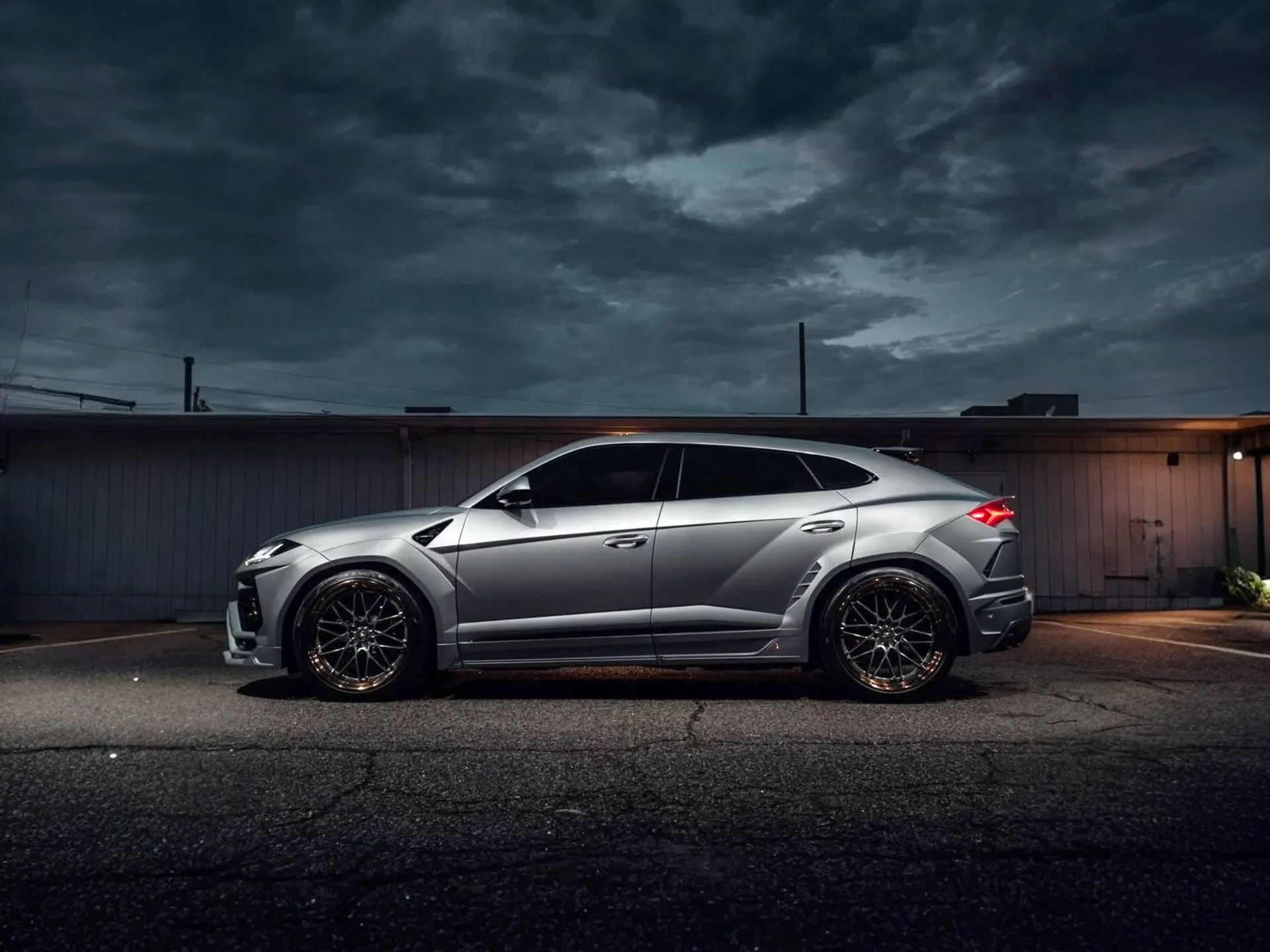 Silver Lamborghini Urus, side profile, dark dramatic sky